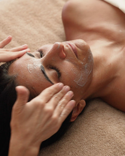 Esthetician applying the French Clay Refining Cleanser to a reclining client