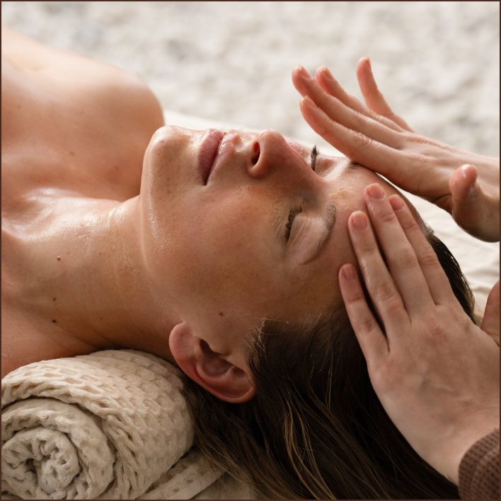 Esthetician applying a thin first pass across a client's face and neck