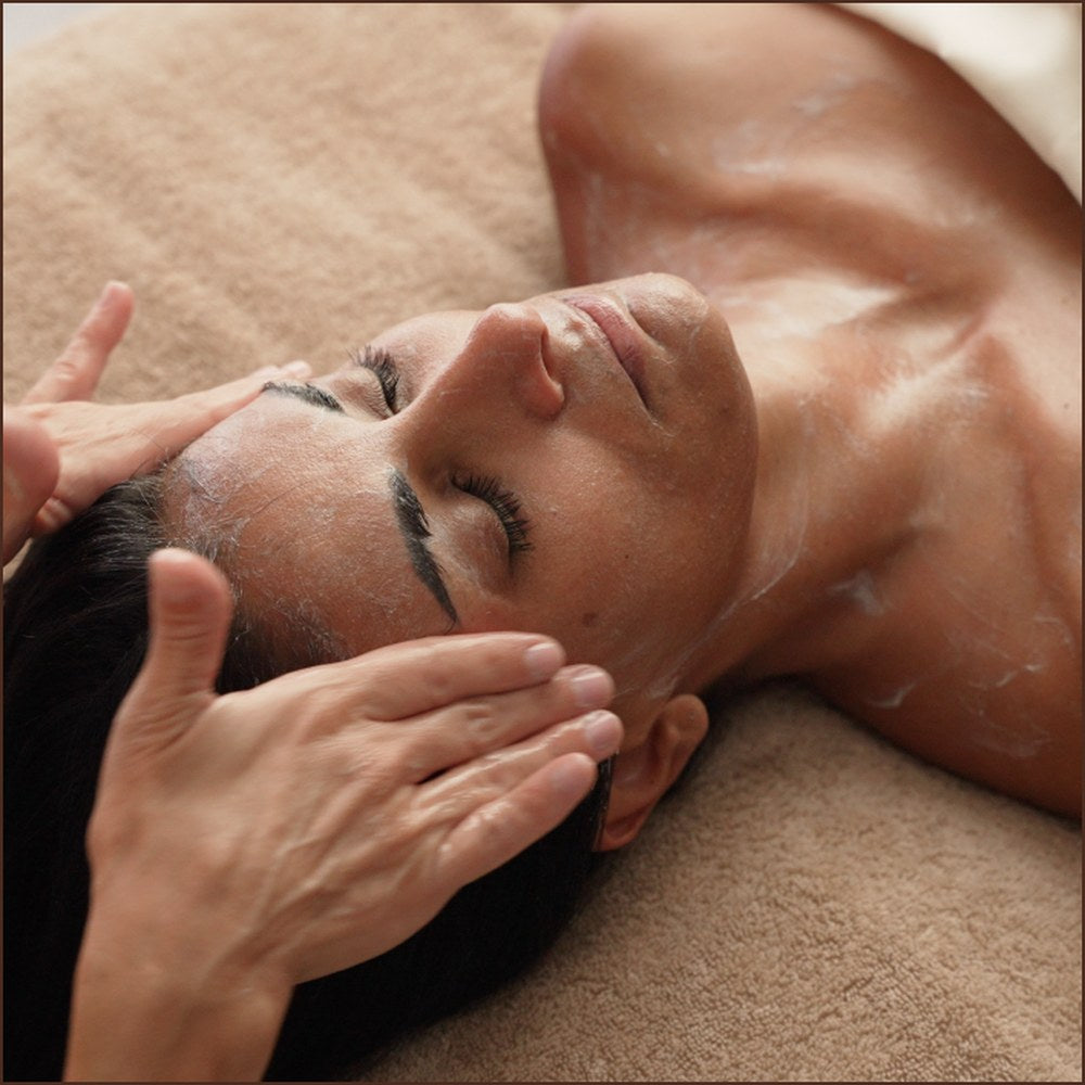 Esthetician massaging the cleanser across a client's face